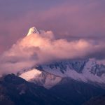 a mountain covered in snow under a cloudy sky