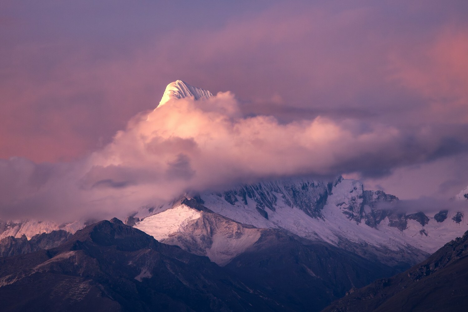 a mountain covered in snow under a cloudy sky